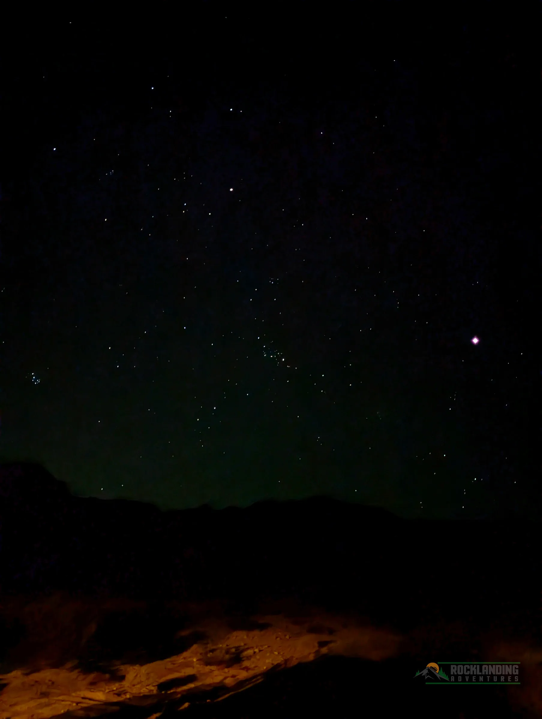 Night sky with stars above a silhouetted desert ridgeline.