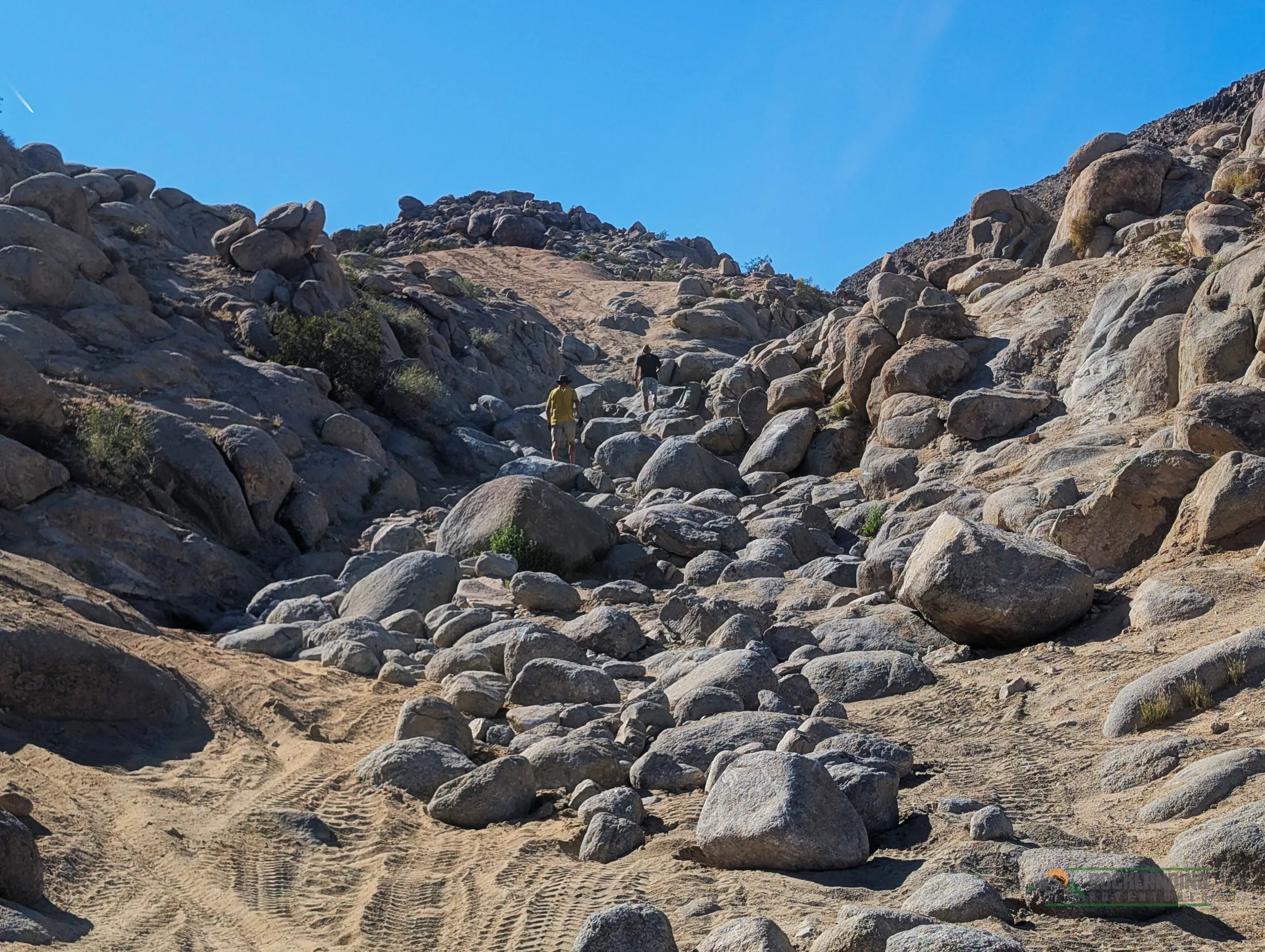 People scouting a rocky trailhead in Johnson Valley.